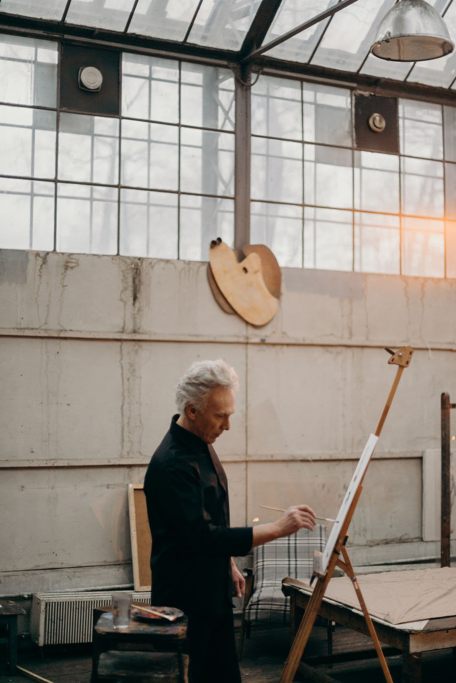 An artist working at an easel in a sunlit studio