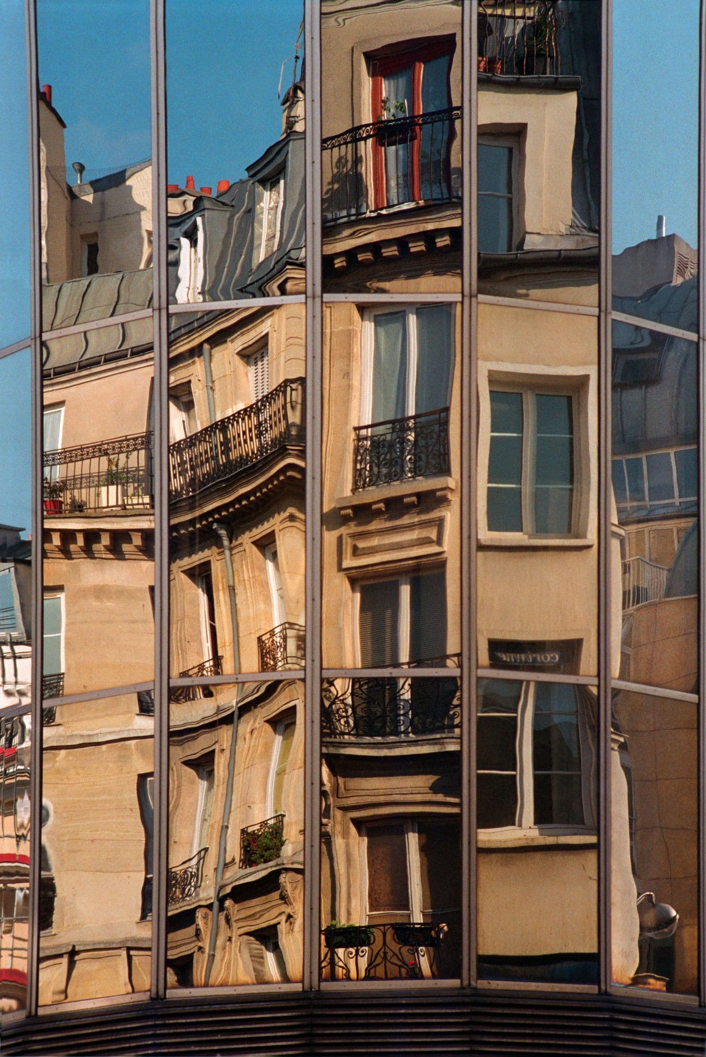 Historic buildings reflected and distorted across a modern glass facade