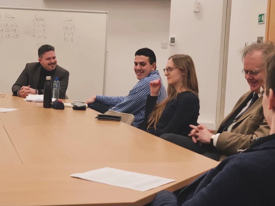 Scholars sharing a conversation around a seminar table.