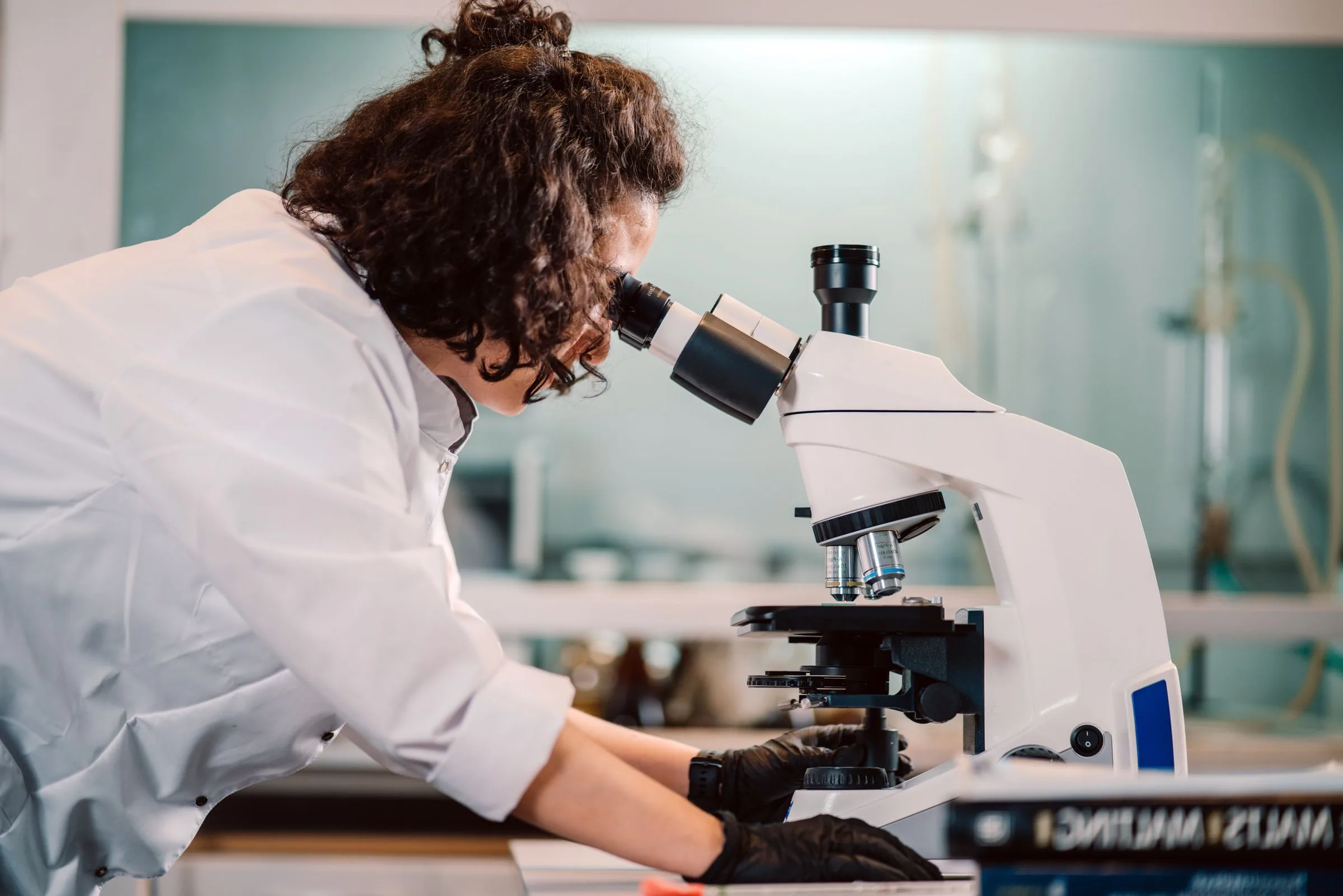 A scientist bent over a microscope in a laboratory