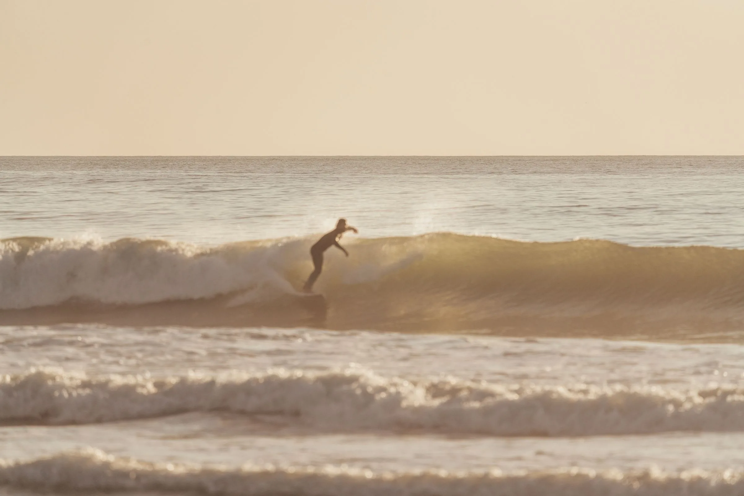 A surfer riding a wave in soft morning light