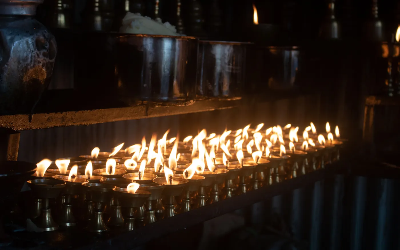 A long row of lit lamps glowing inside a temple