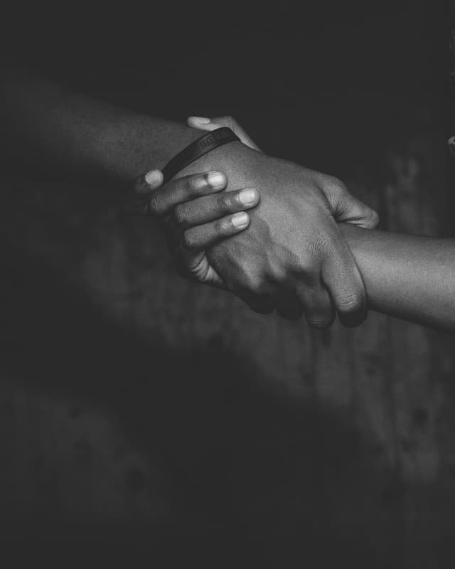 Black-and-white close-up of two hands holding each other.