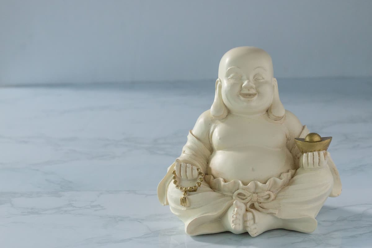 Close-up of a Laughing Buddha figurine on a marble surface.