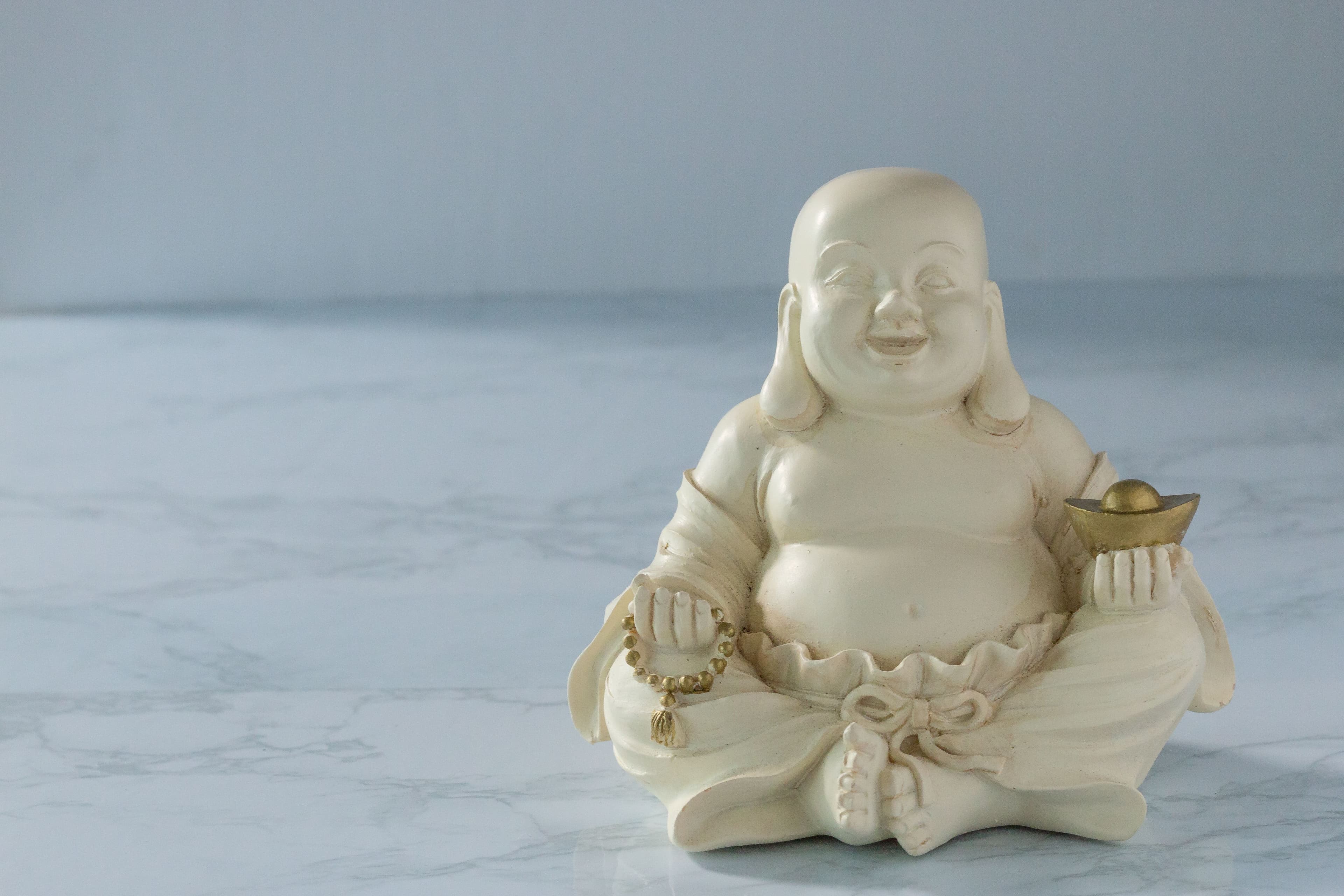 Close-up of a Laughing Buddha figurine on a marble surface.