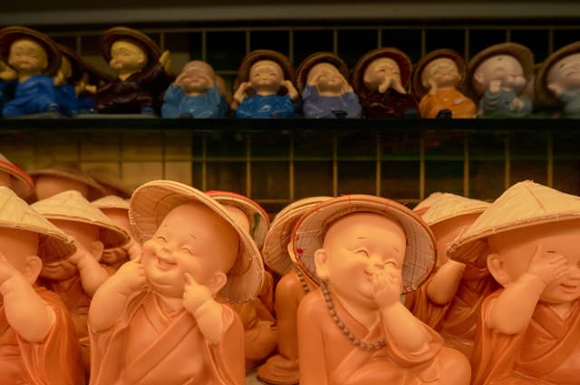 Smiling decorative monk statues wearing traditional attire and hats.