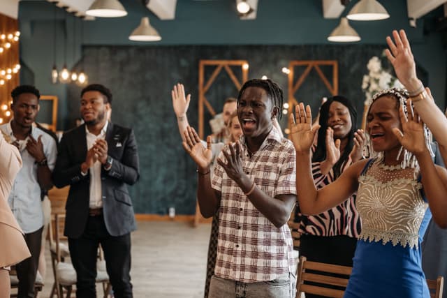 A group of people standing, clapping and singing together.