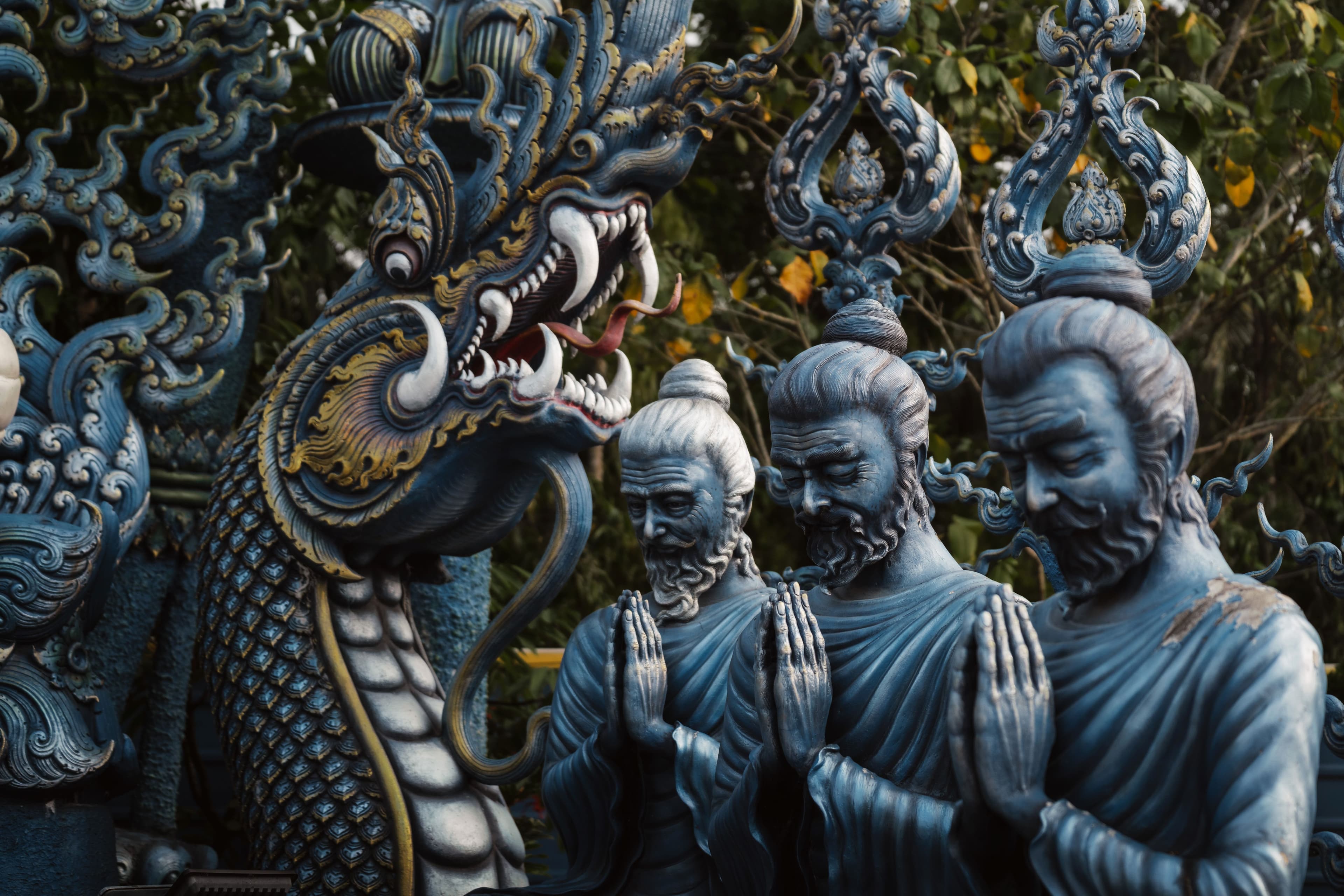 Detailed blue statues and a dragon sculpture outdoors.