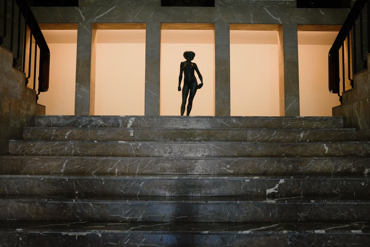A statue silhouetted behind marble stairs at night in Porto, Portugal.