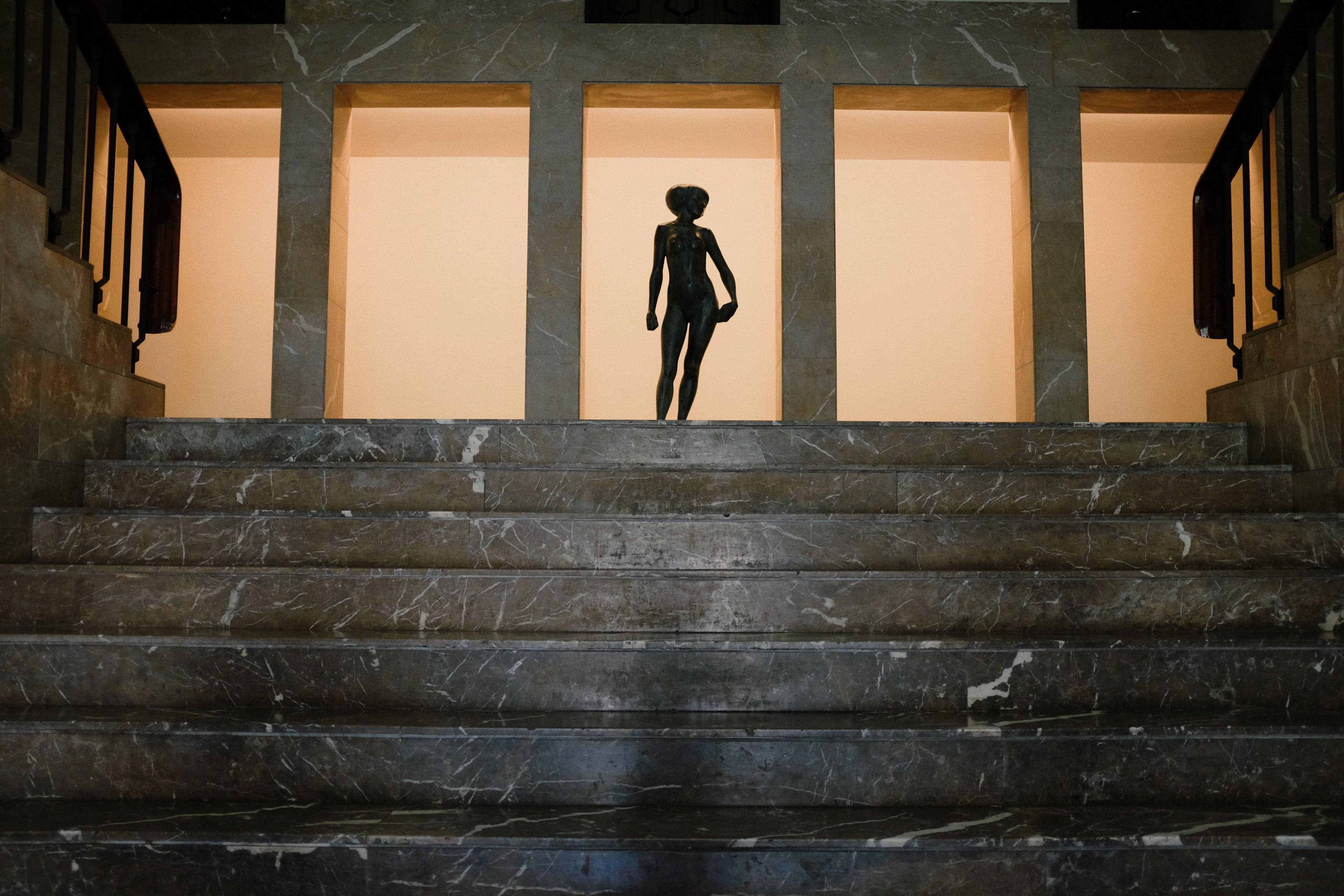 A statue silhouetted behind marble stairs at night in Porto, Portugal.