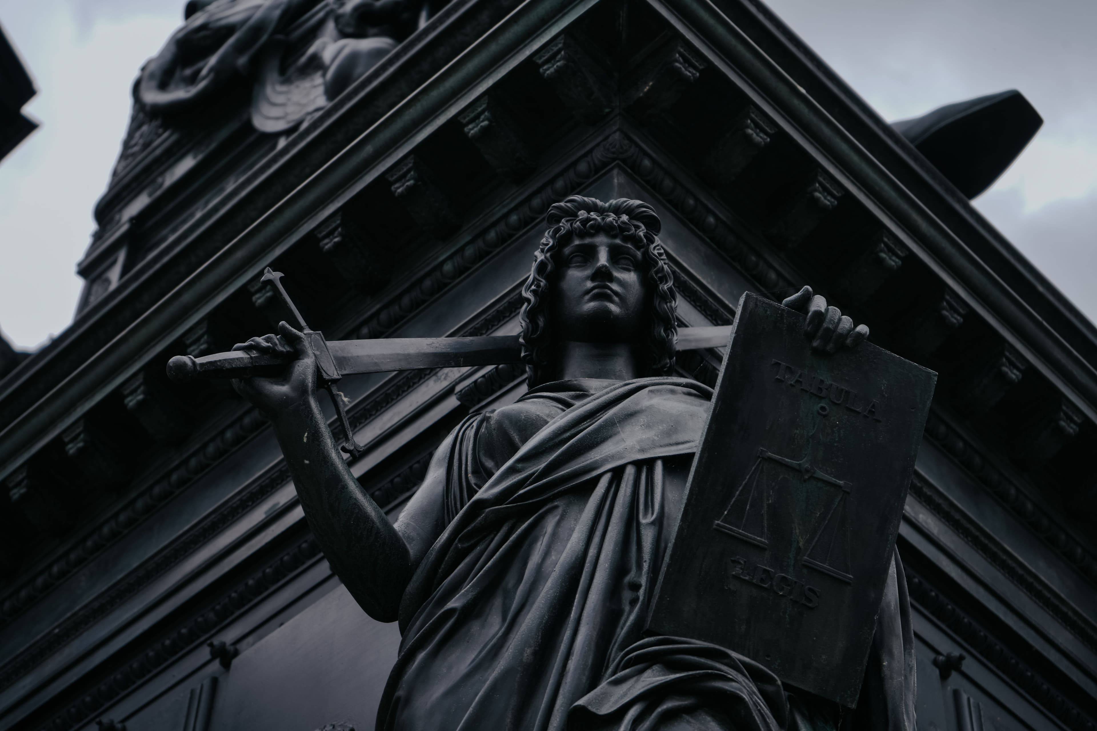 Black-and-white photograph of a Lady Justice statue holding a sword and scales in Dresden, Germany.