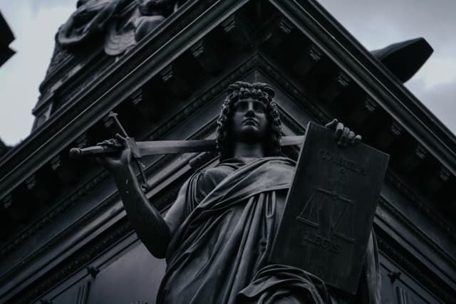 Black-and-white photograph of a Lady Justice statue holding a sword and scales in Dresden, Germany.